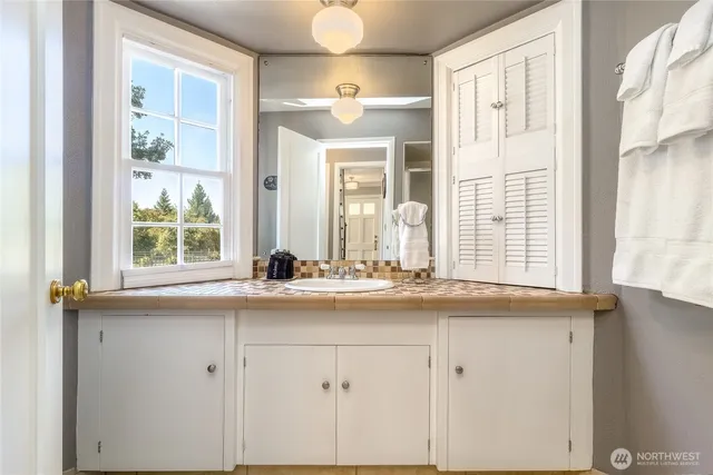 a bathroom with a granite countertop sink and a window
