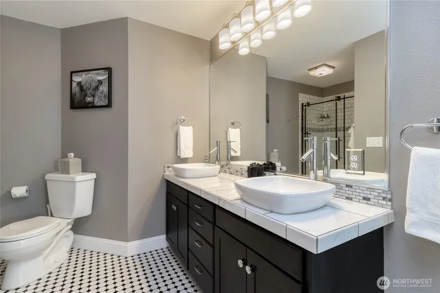 a bathroom with a sink a toilet a mirror and shower