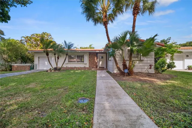 a view of a house with a small yard and palm trees
