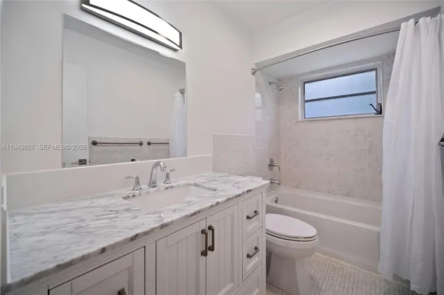 a bathroom with a granite countertop sink a toilet and shower