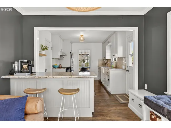 a kitchen with stainless steel appliances granite countertop a table chairs and white cabinets