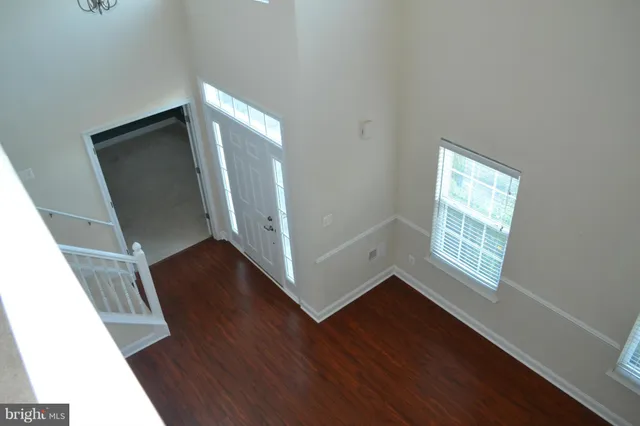 an empty room with wooden floor fireplace and windows