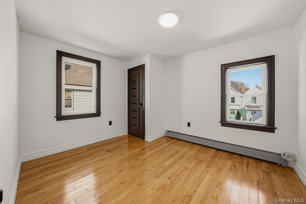 118-27 201st Street Queens, NY 11412 - Photo 18 of 36 a view of an empty room with window and wooden floor