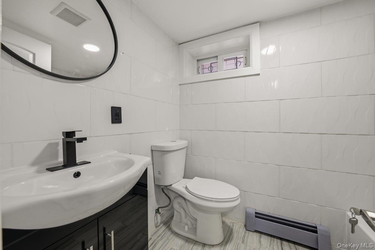 118-27 201st Street Queens, NY 11412 - Photo 31 of 36 a bathroom with a toilet sink and mirror