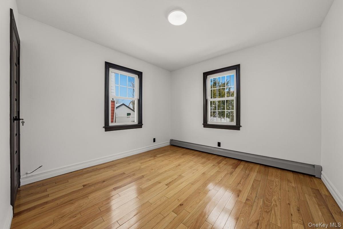 118-27 201st Street Queens, NY 11412 - Photo 8 of 36 an empty room with wooden floor and windows