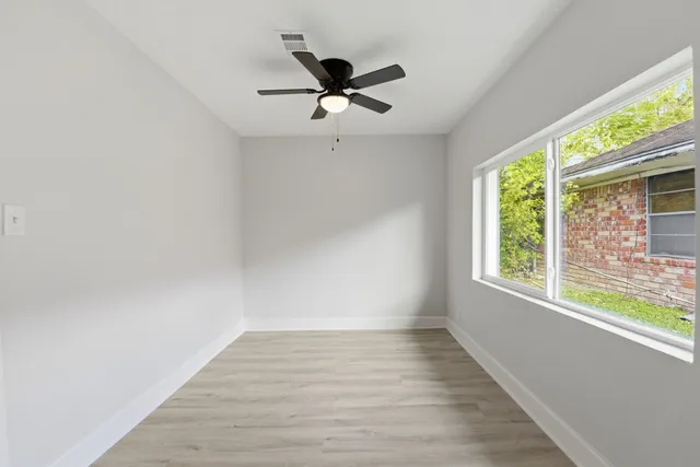 a view of empty room with wooden floor and fan