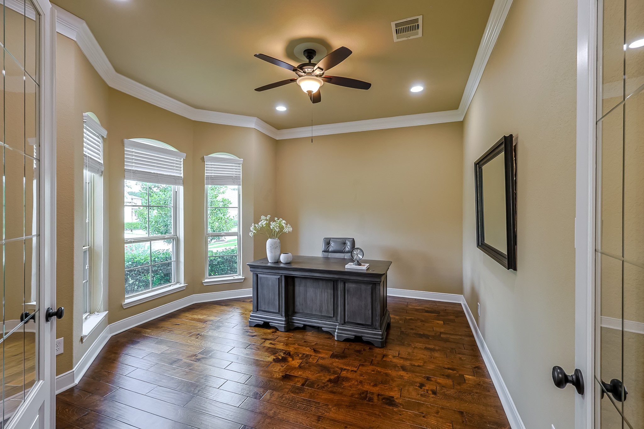 515 Mill Creek Road Pinehurst, TX 77362 - Photo 6 of 48 This home office features rich hardwood floors, neutral walls, and a ceiling fan. It offers ample natural light through three large windows, accented by elegant crown molding.