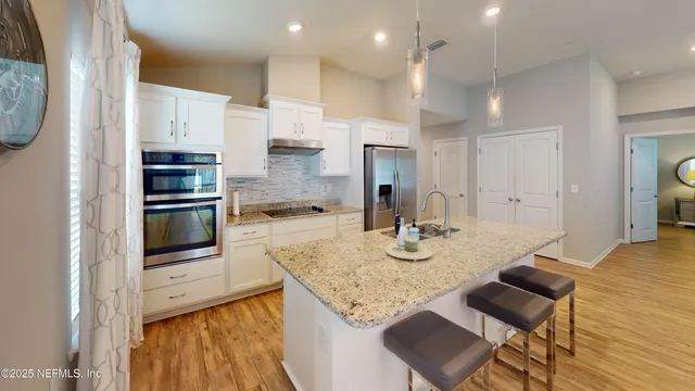 a kitchen with stainless steel appliances granite countertop a stove refrigerator and a sink