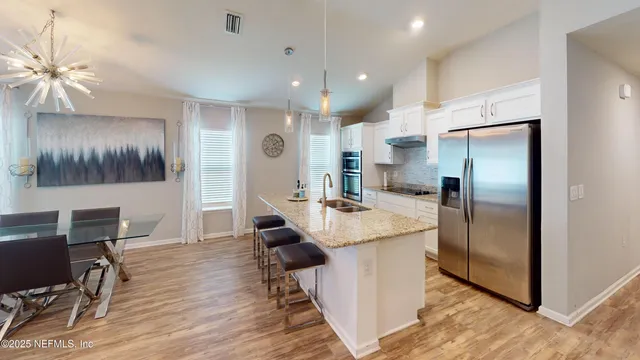 a kitchen with kitchen island a refrigerator stove and a dining table with wooden floor