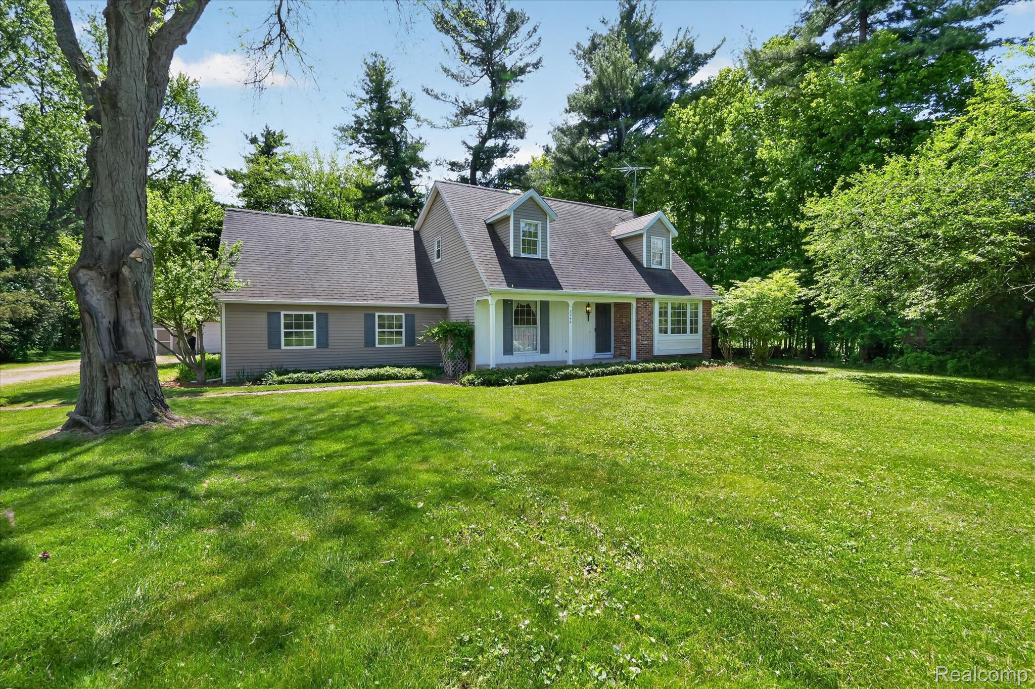 2240 Peppermill Road Lapeer, MI 48446 - Photo 5 of 11 Cape cod-style house featuring a porch, a front yard, and view of wooded area