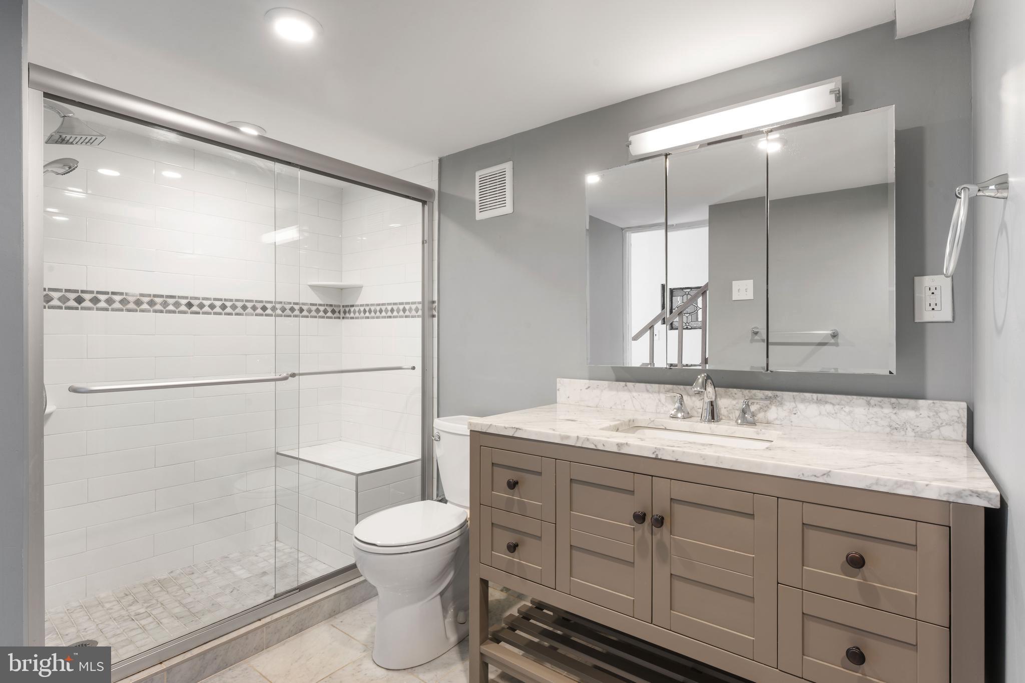 700 South 10th Street, Unit 2F Philadelphia, PA 19147 - Photo 24 of 40 a bathroom with a granite countertop sink a toilet a mirror and shower