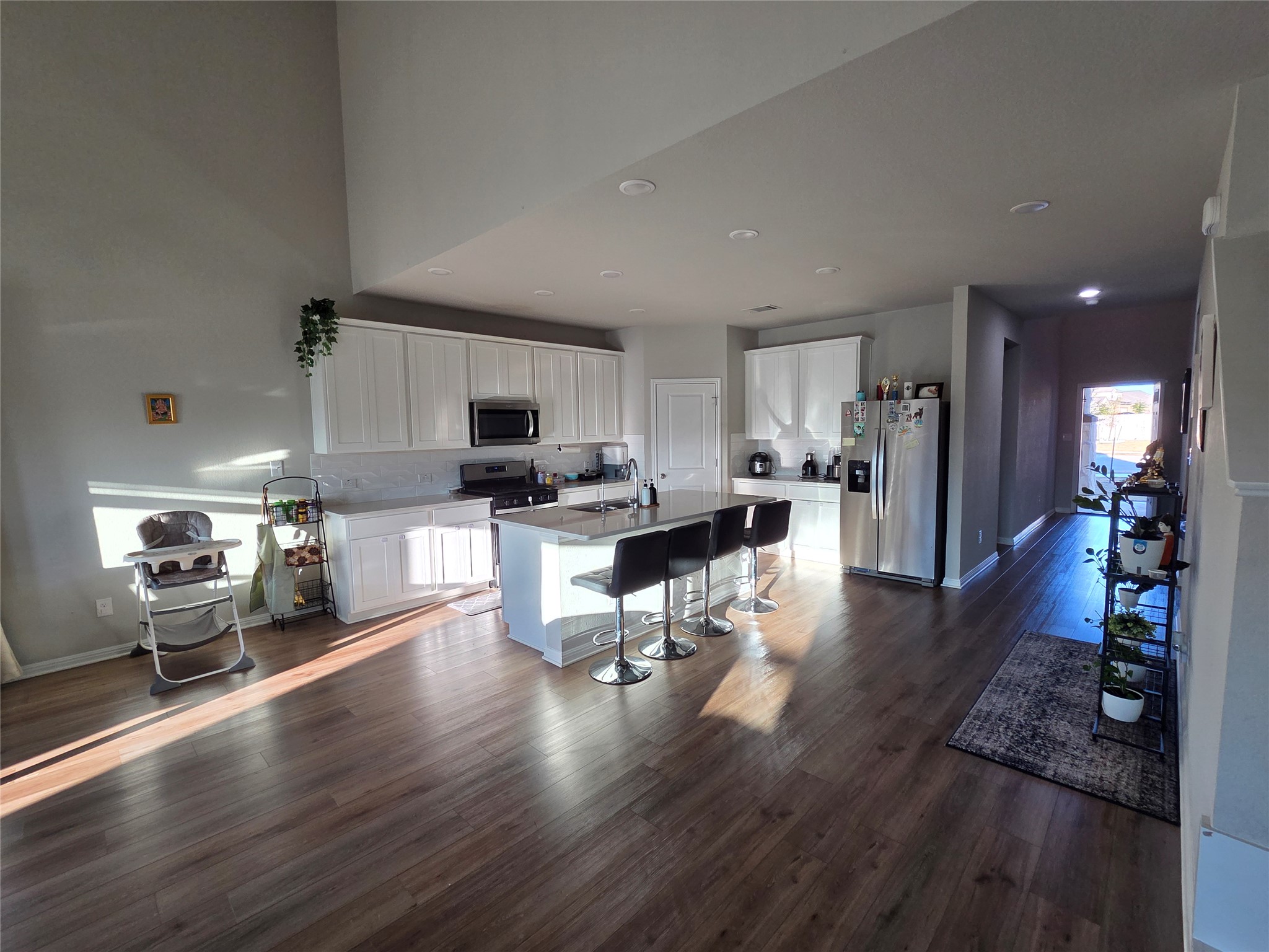 300 Windy Reed Road Hutto, TX 78634 - Photo 9 of 24 a kitchen with stainless steel appliances kitchen island granite countertop a refrigerator a stove top oven a dining table and chairs with wooden floor