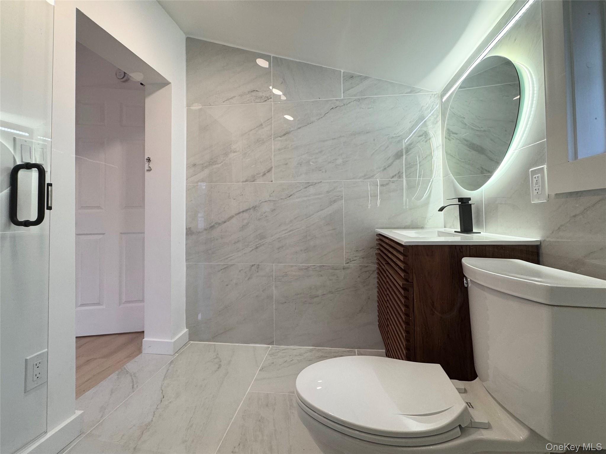 88 Cold Spring Road Liberty, NY 12754 - Photo 26 of 32 Bathroom with vanity, marble look tile flooring, and tile walls