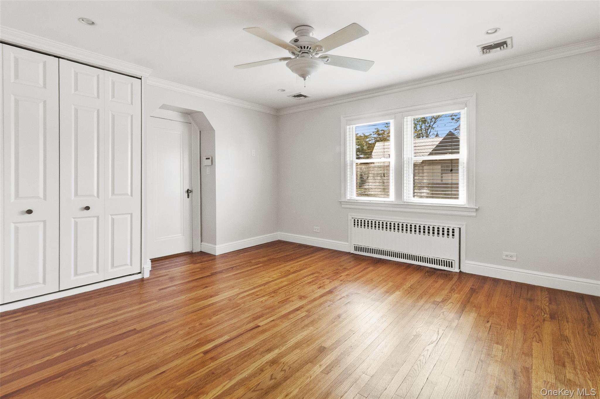 11 Crawford Street Yonkers, NY 10705 - Photo 13 of 24 Unfurnished bedroom featuring arched walkways, crown molding, radiator, light wood finished floors, and a closet