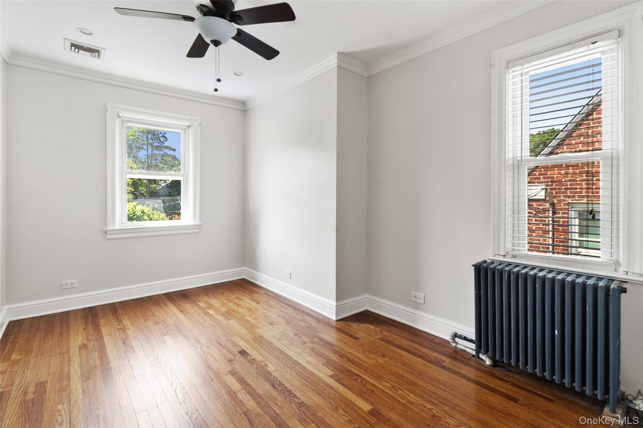 11 Crawford Street Yonkers, NY 10705 - Photo 15 of 24 Empty room with radiator heating unit, hardwood / wood-style floors, ornamental molding, and a ceiling fan