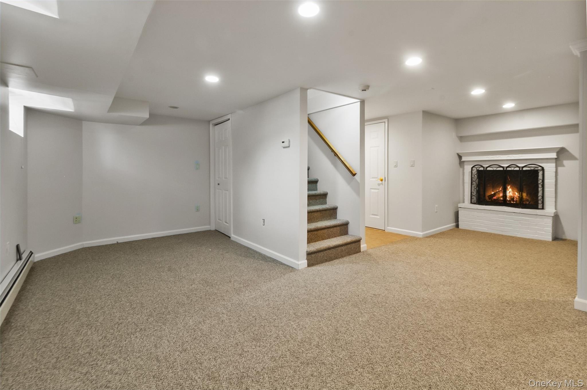 11 Crawford Street Yonkers, NY 10705 - Photo 18 of 24 Finished below grade area with light carpet, a brick fireplace, recessed lighting, stairs, and a baseboard heating unit