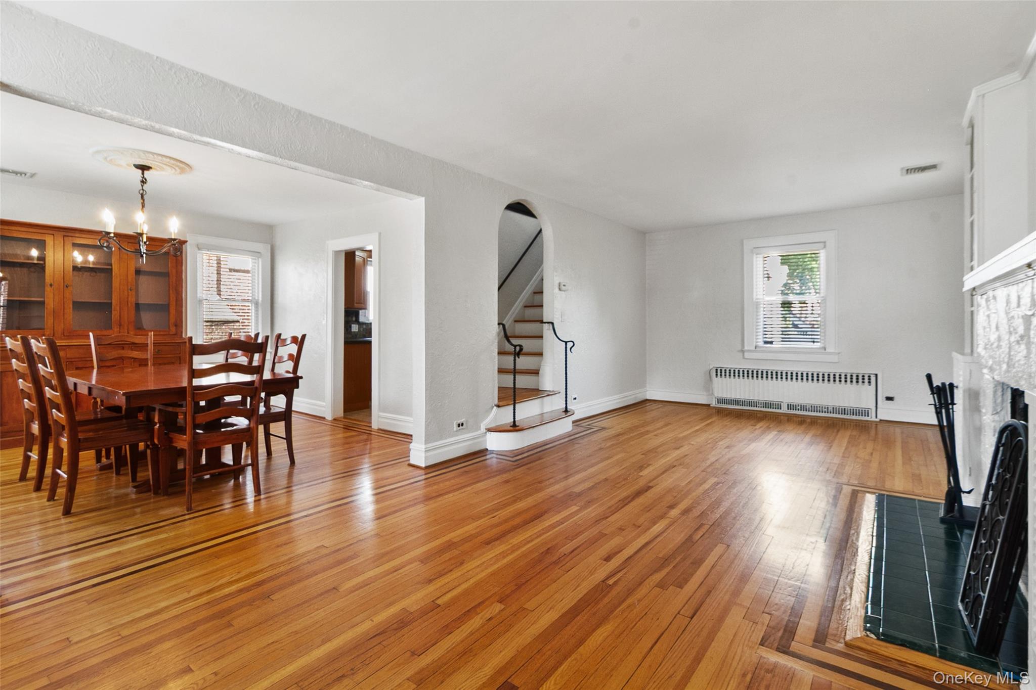 11 Crawford Street Yonkers, NY 10705 - Photo 5 of 24 Living room featuring stairway, light wood-style floors, radiator, a chandelier, and a fireplace with flush hearth