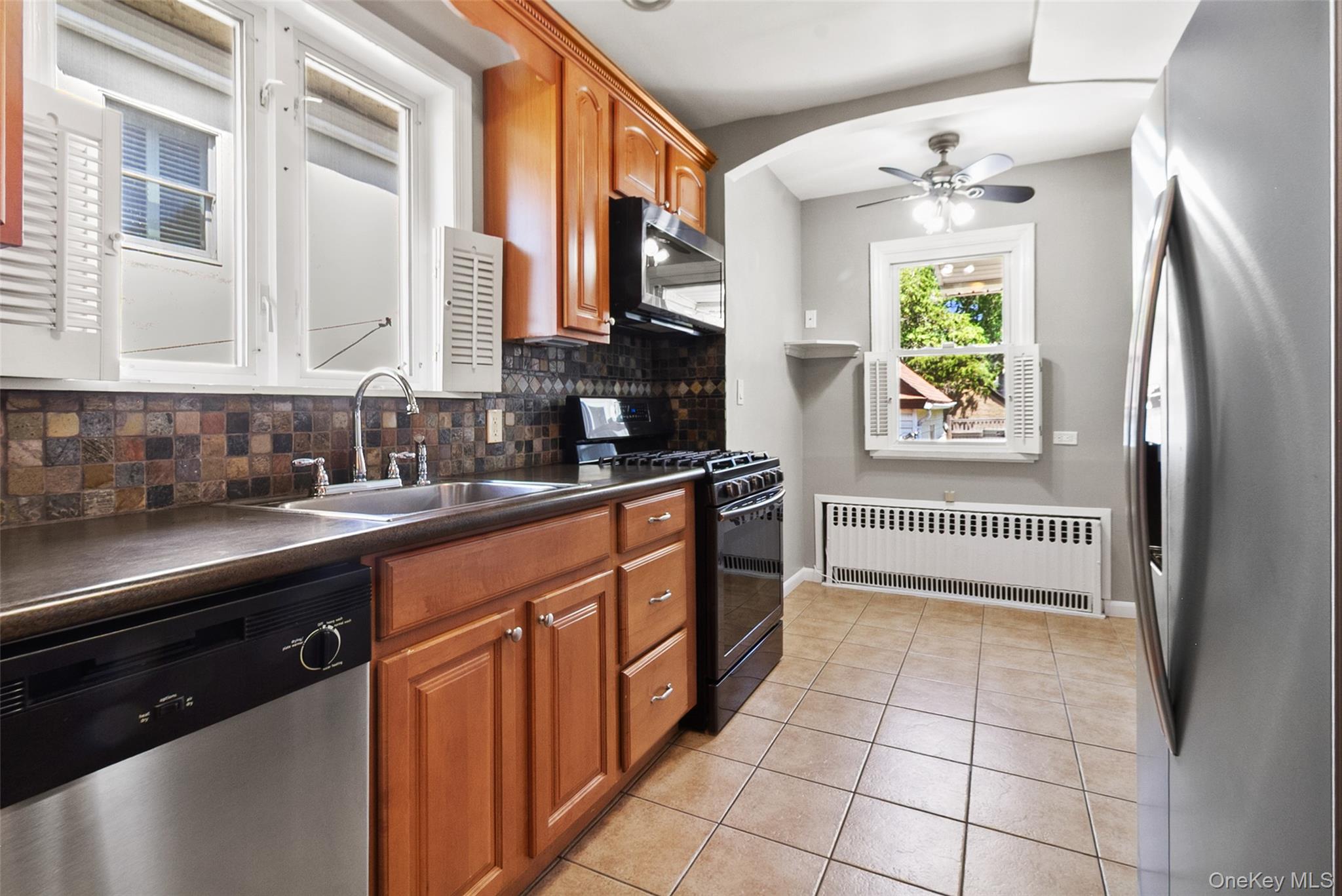 11 Crawford Street Yonkers, NY 10705 - Photo 10 of 24 Kitchen featuring stainless steel appliances, brown cabinetry, backsplash, and light tile patterned floors