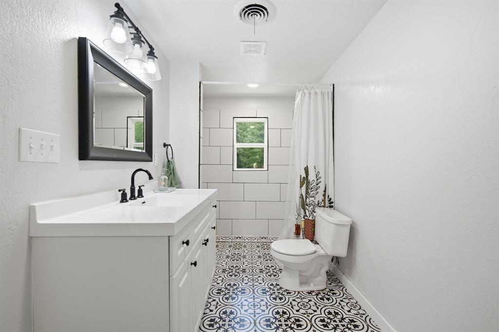 3325 Dove Creek Road Cleburne, TX 76031 - Photo 8 of 40 Bathroom featuring a vanity with integrated sink, black framed mirror, black fixtures, patterned floor tile, and white subway tile shower surround