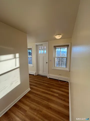 a view of an empty room with wooden floor and a window