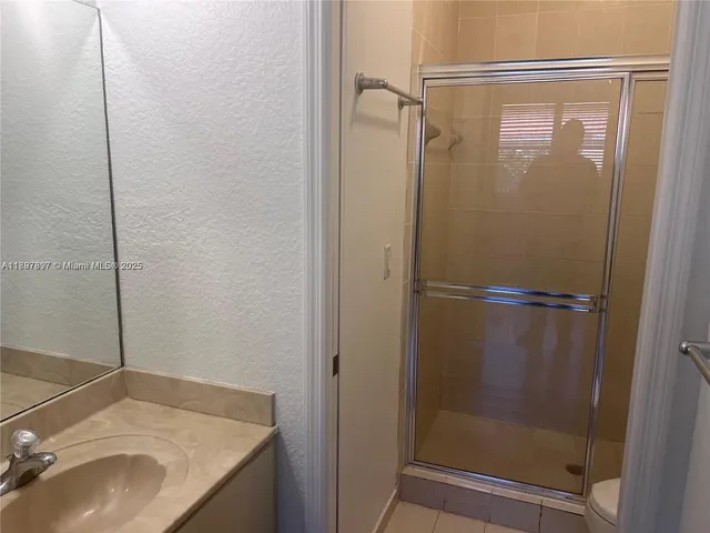 a bathroom with a granite countertop shower and a sink