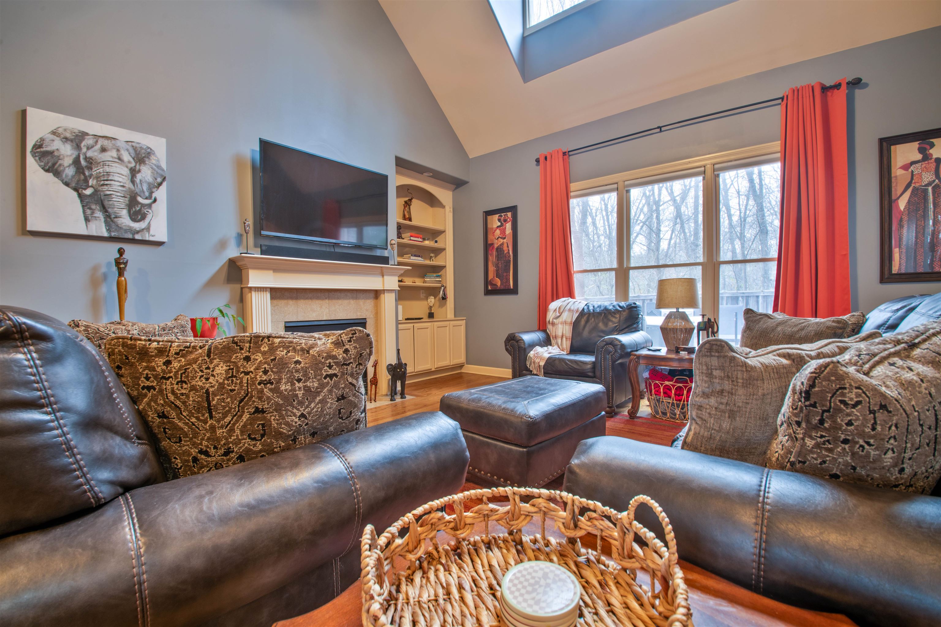 8722 Brunswick Forest Drive Bartlett, TN 38133 - Photo 6 of 38 Living room featuring built in features, a tile fireplace, hardwood / wood-style floors, a skylight, and high vaulted ceiling