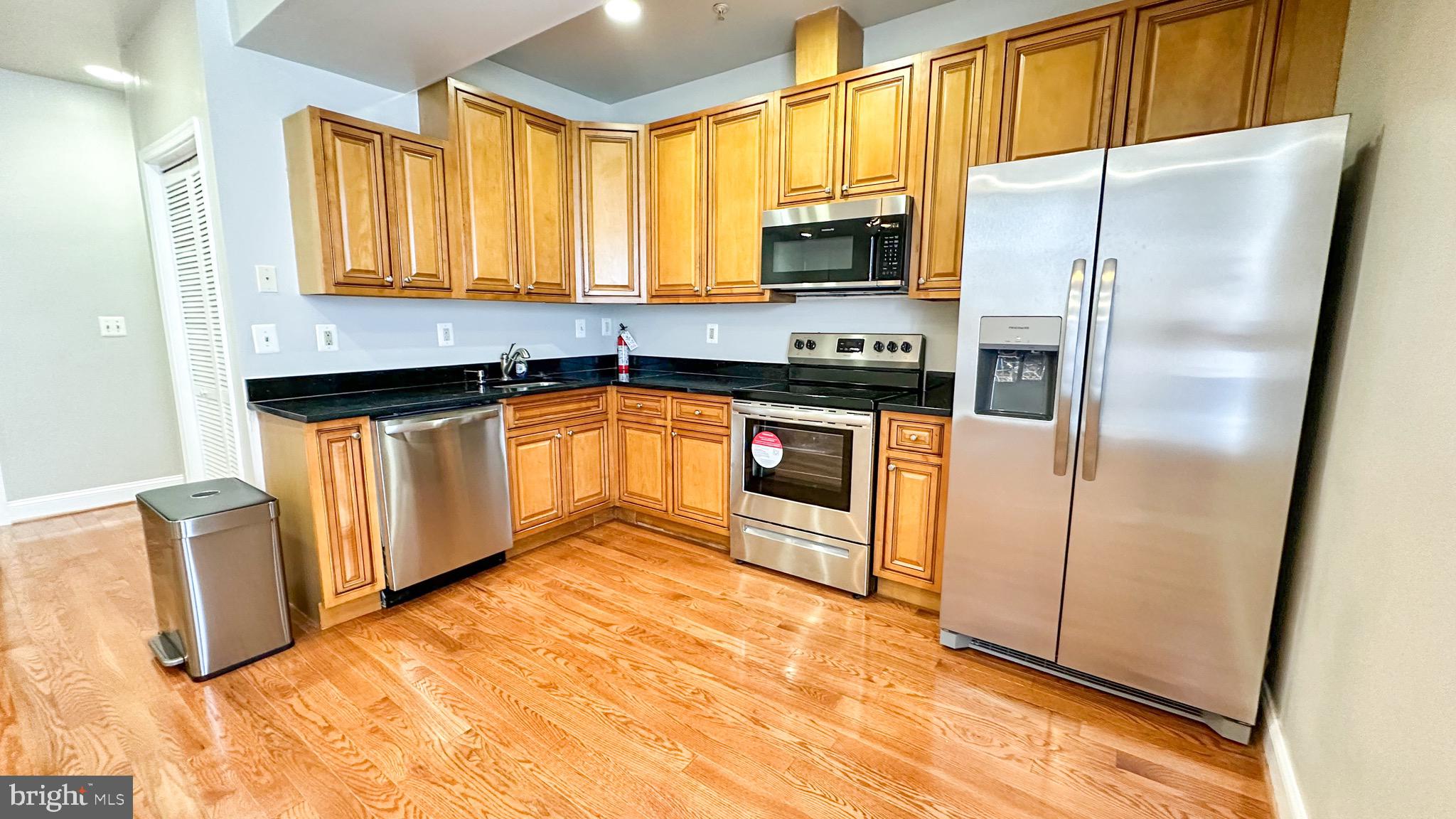 3408 Sherman Avenue Northwest, Unit 101 Washington, DC 20010 - Photo 5 of 15 a kitchen with granite countertop a refrigerator and a stove top oven