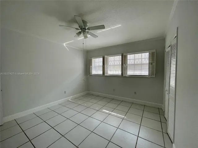 an empty room with windows and ceiling fan