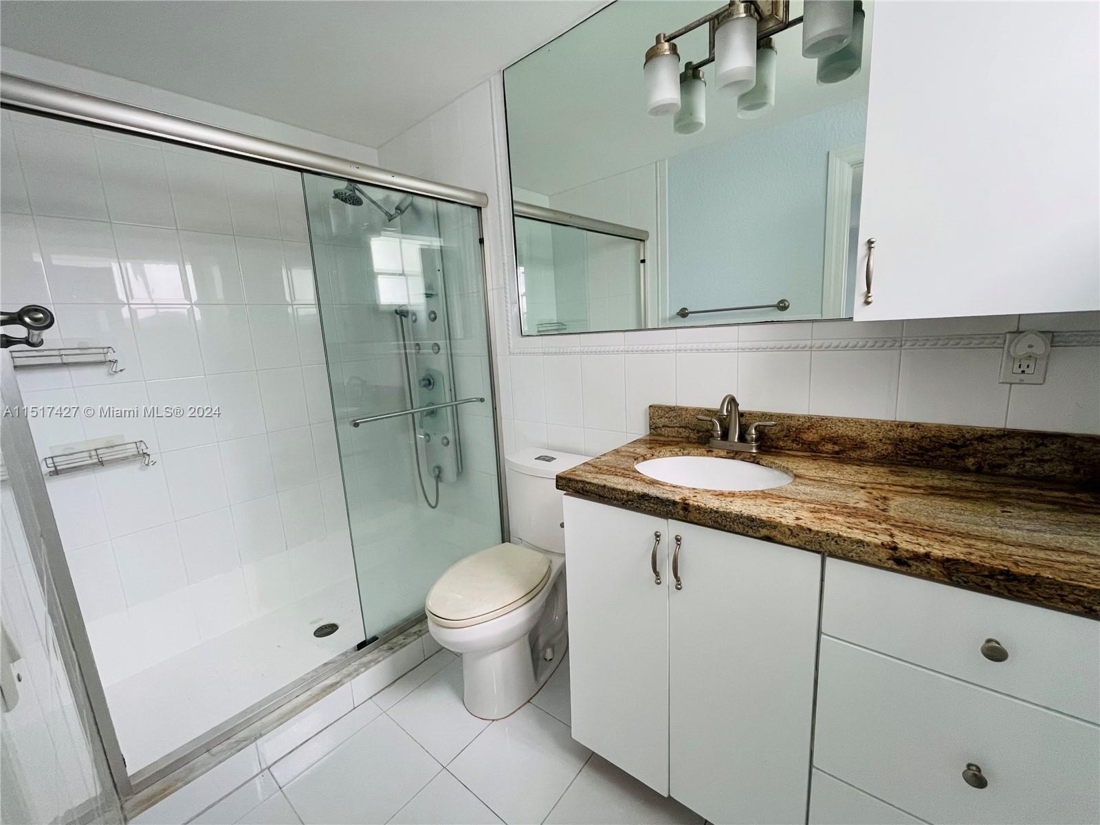 462 Golden Isles Drive, Unit 210 Hallandale Beach, FL 33009 - Photo 39 of 41 a bathroom with a granite countertop sink toilet and shower