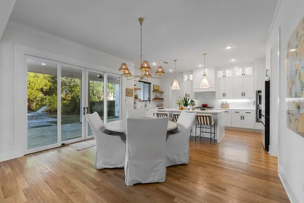 a view of a dining room and livingroom with furniture wooden floor a chandelier