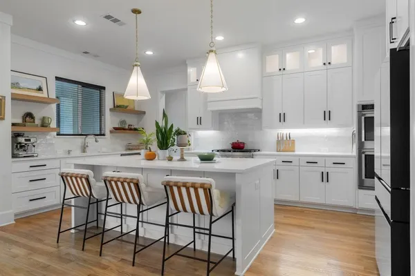 a kitchen with stainless steel appliances granite countertop a table chairs sink refrigerator and cabinets
