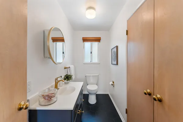 a bathroom with a toilet a sink a mirror and vanity