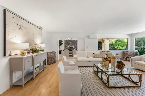 a living room with furniture large window and wooden floor