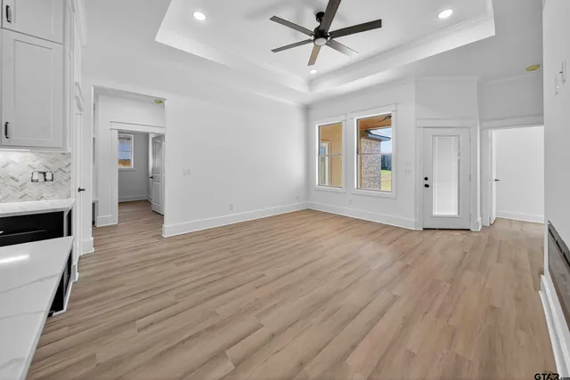a view of empty room with wooden floor and fan