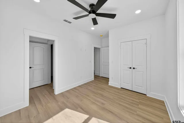 a view of empty room with wooden floor and fan