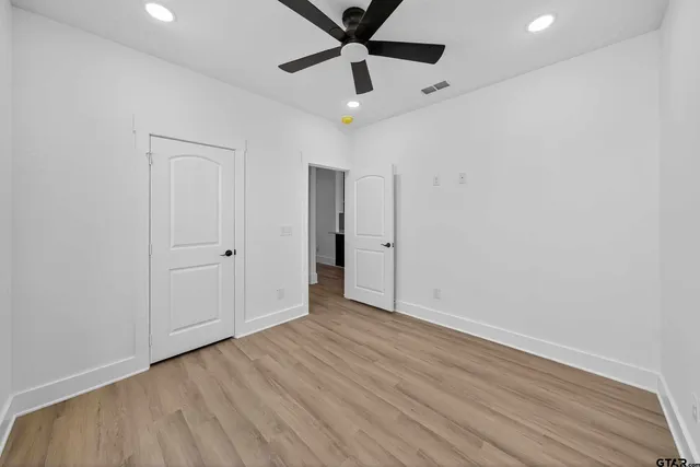 a view of empty room with wooden floor and fan