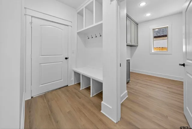 an empty room with wooden floor ceiling fan and windows