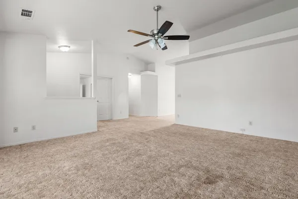 a view of a livingroom with a ceiling fan & kitchen view