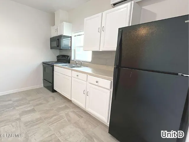 a kitchen with stainless steel appliances a refrigerator a sink and white cabinets