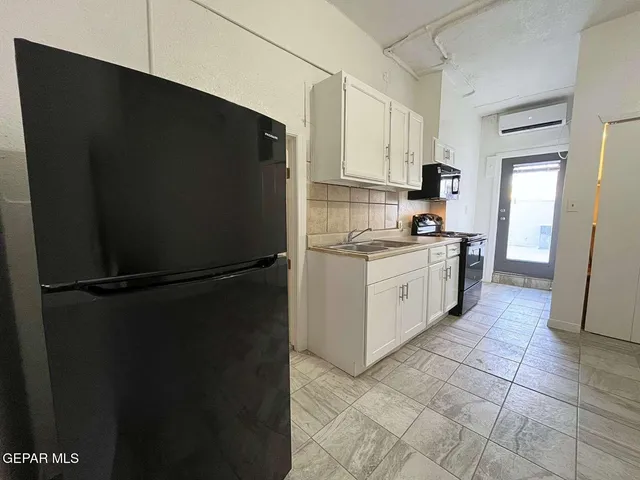 a kitchen with a refrigerator and white cabinets