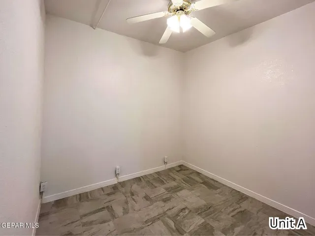 an empty room with a chandelier fan and windows