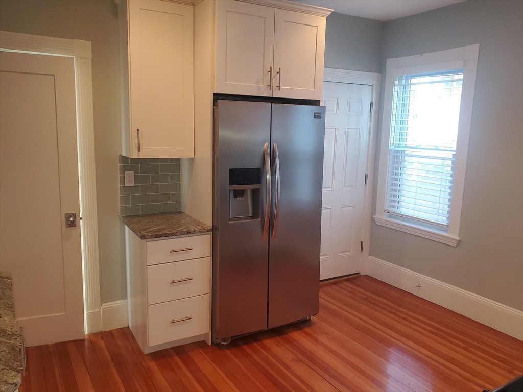 14 North Munroe Terrace, Unit 2 Boston, MA 02122 - Photo 3 of 19 a kitchen with wooden floors and white cabinets