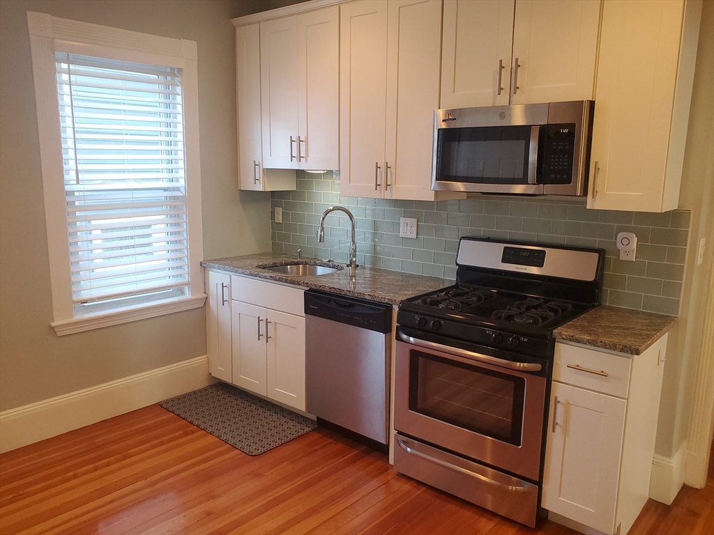 14 North Munroe Terrace, Unit 2 Boston, MA 02122 - Photo 4 of 19 a kitchen with granite countertop wooden cabinets and a stove