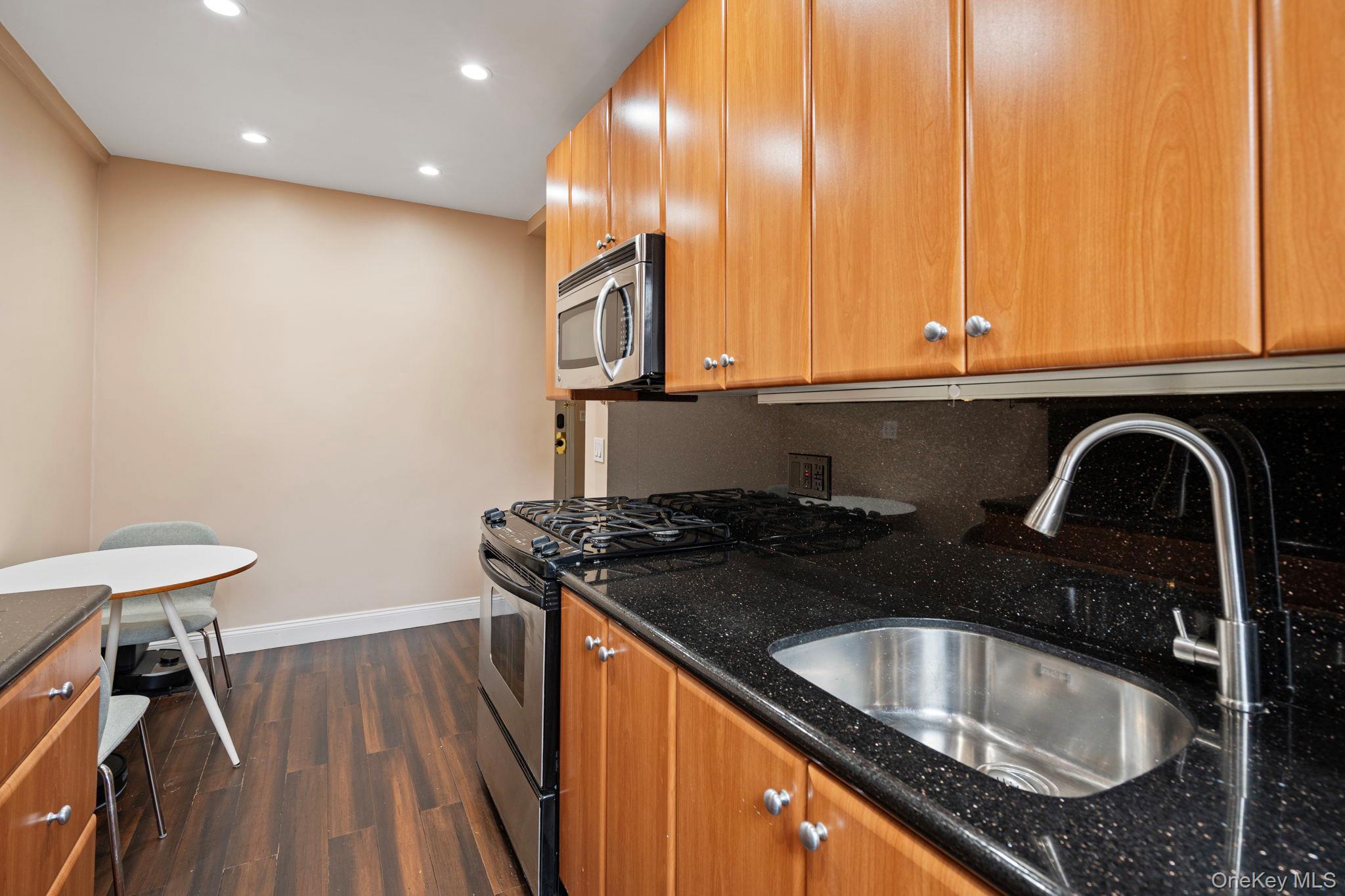 77-15 Ditmars Boulevard, Unit B2 Queens, NY 11370 - Photo 16 of 24 a kitchen with granite countertop a sink a stove and cabinets