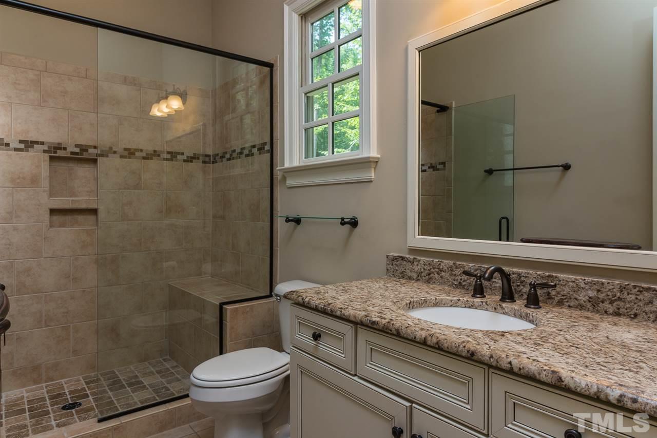 8841 Stage Ford Road Raleigh, NC 27615 - Photo 18 of 25 a bathroom with a granite countertop sink a toilet and shower