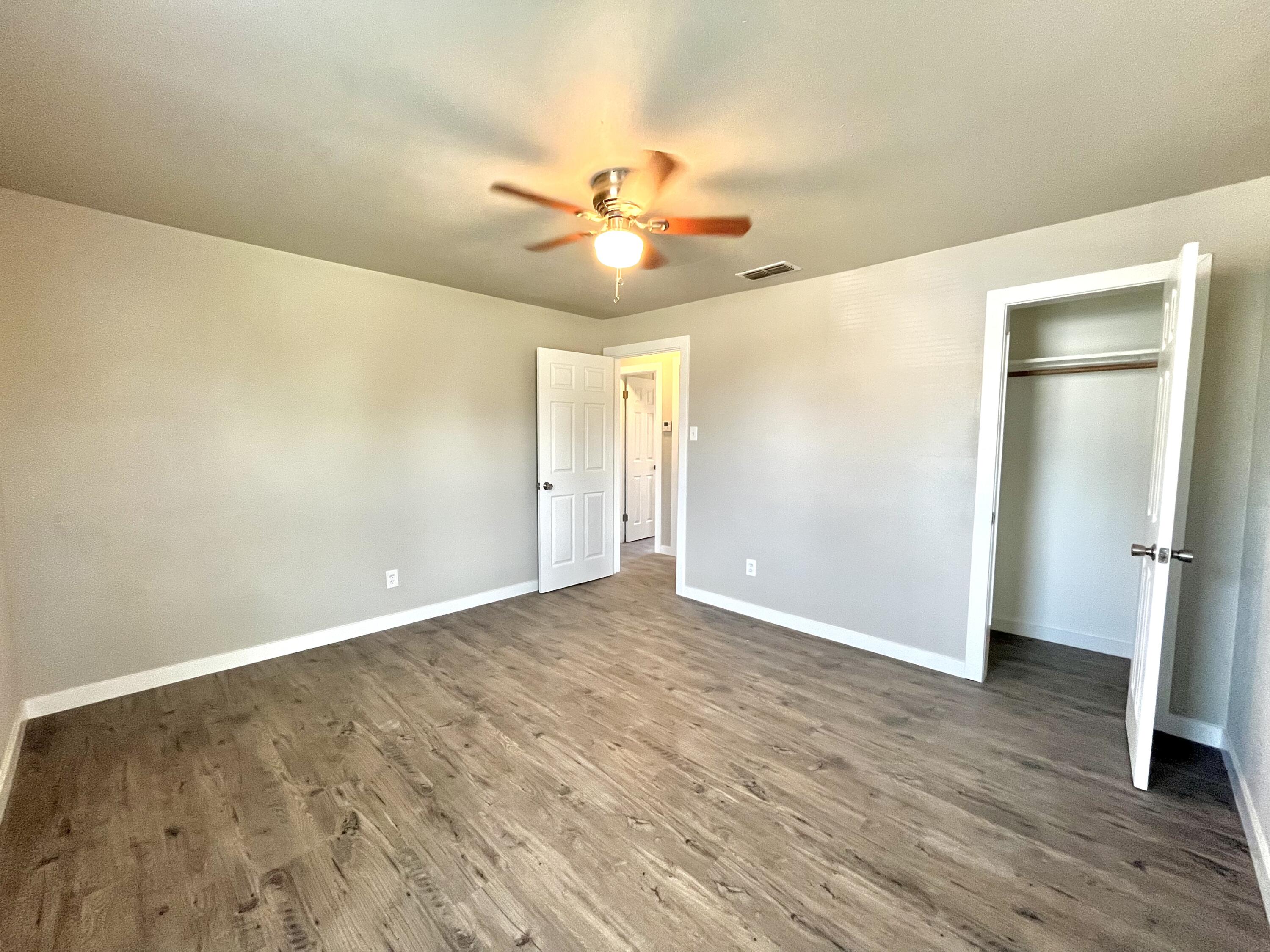 1510 East 10th Street Lubbock, TX 79403 - Photo 4 of 6 an empty room with wooden floor and a ceiling fan