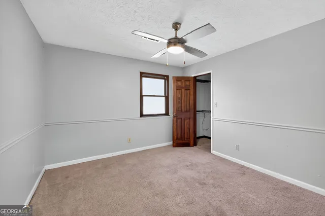 an empty room with windows and chandelier fan