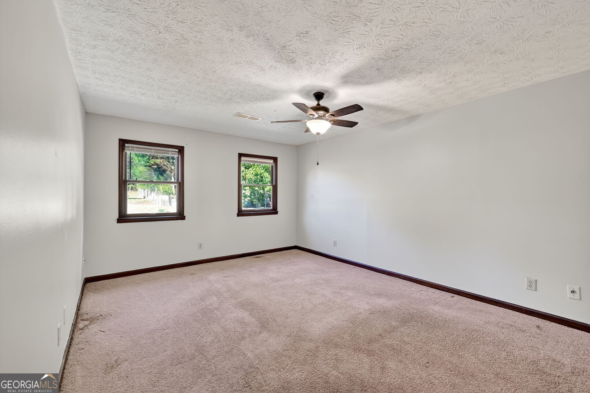 1378 Stoneleigh Hill Road Lithonia, GA 30058 - Photo 23 of 32 an empty room with windows and chandelier fan