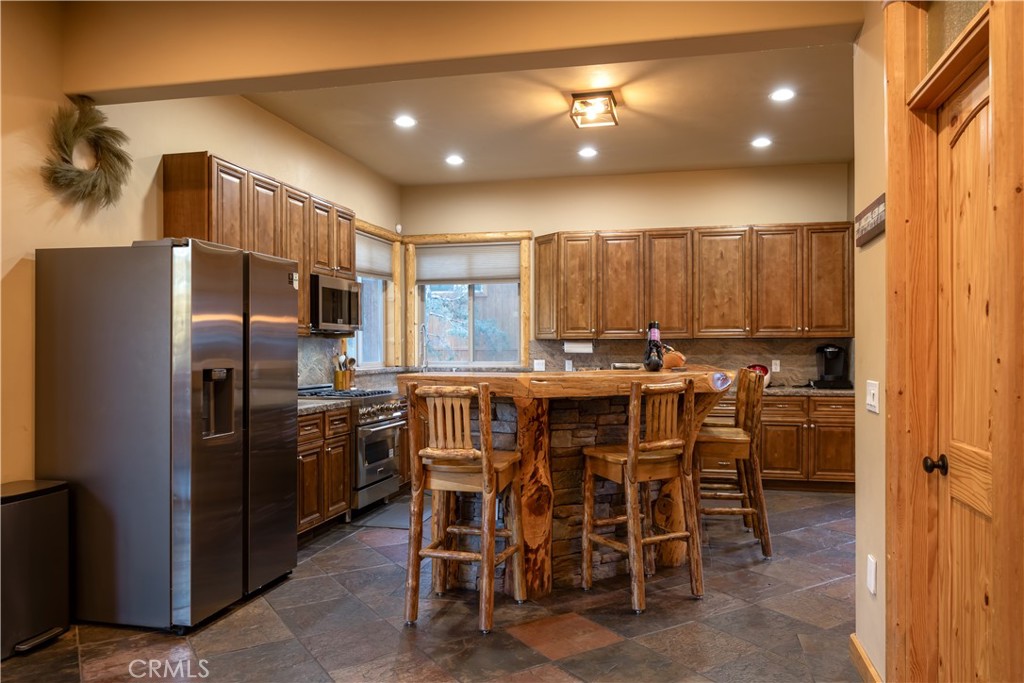 325 Stony Creek Road Big Bear Lake, CA 92315 - Photo 8 of 42 a kitchen with a table chairs refrigerator and cabinets