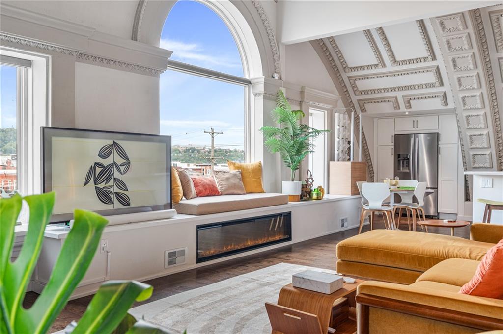 2132 Sarah Street, Unit 207 Pittsburgh, PA 15203 - Photo 8 of 50 The open-concept living space is bathed in natural light, featuring a cozy fireplace and a built-in window seat, perfect for enjoying the vibrant city views.